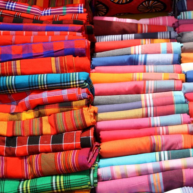 on the left - a stack of beautiful and colourful traditional Shuka blankets that the male masai use as garments. on the right - a stack of beautiful and colourful kikoys which are what the woman use as a scarf