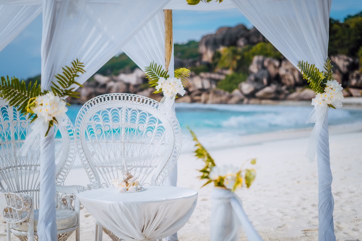 wedding signage place with white arch around it overlooking the beach. beautiful sunny day.